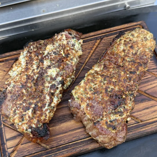 Finished New York Strip steaks with golden Herb Parmesan Crust.