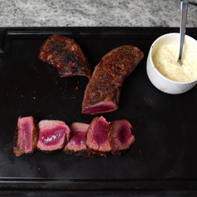 Top-down view of sliced medium-rare beef tenderloin with a seared crust.