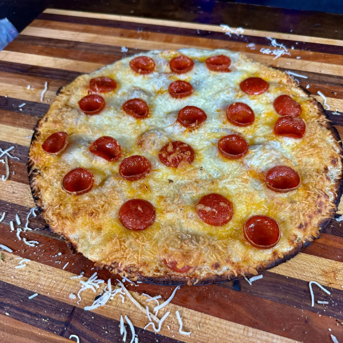 Thin-crust pepperoni pizza with melted cheese on a cutting board