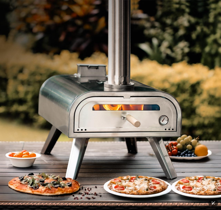 Outdoor wood-fired pizza oven on patio table with flame and baked pizzas