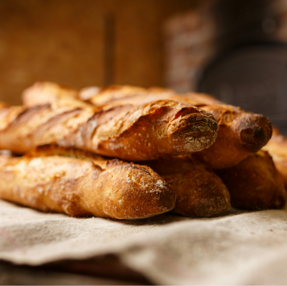 A pile of freshly baked baguettes on a cloth.