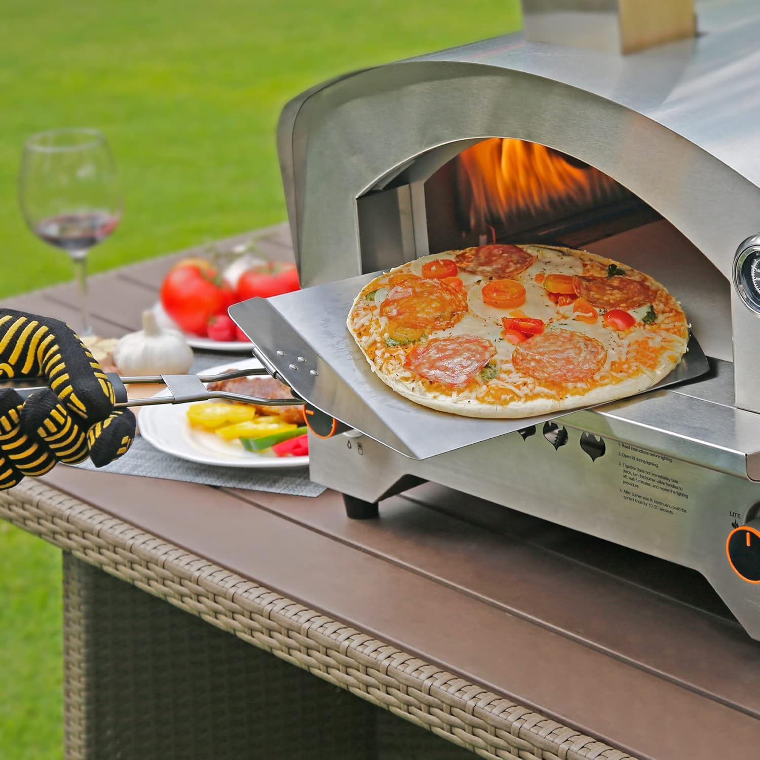 Big Horn Outdoors pizza being removed from stainless steel oven with pizza peel, ideal for homemade pizza.