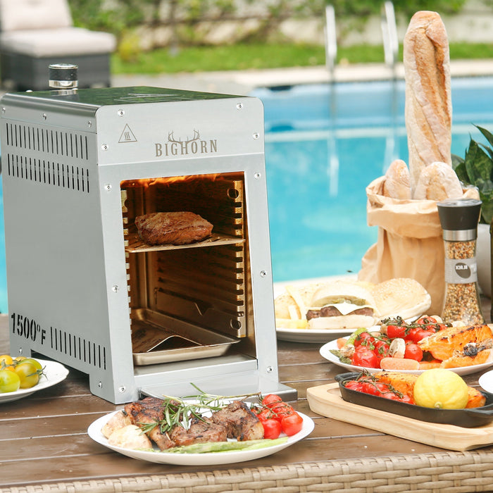 portable infrared grill on patio table by pool with steak and BBQ sides
