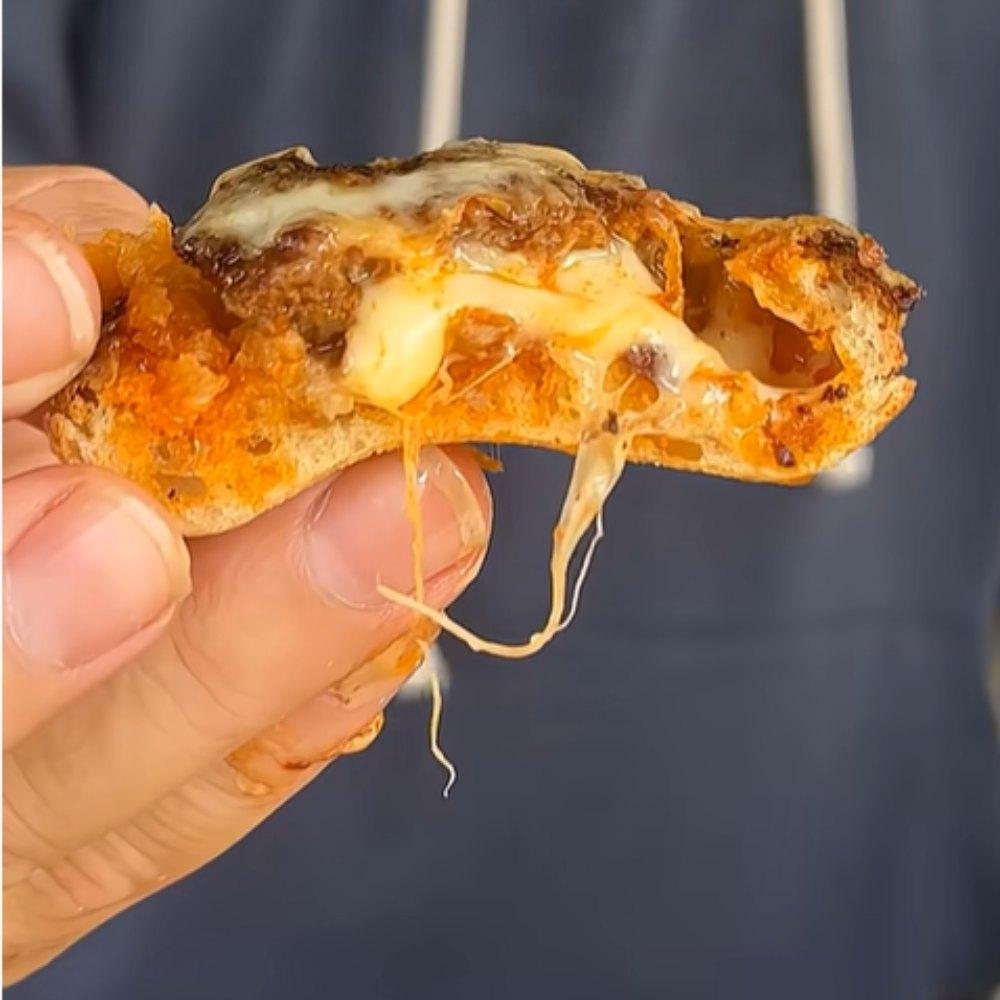 Crispy bite with gooey melted cheese pull, held by hand