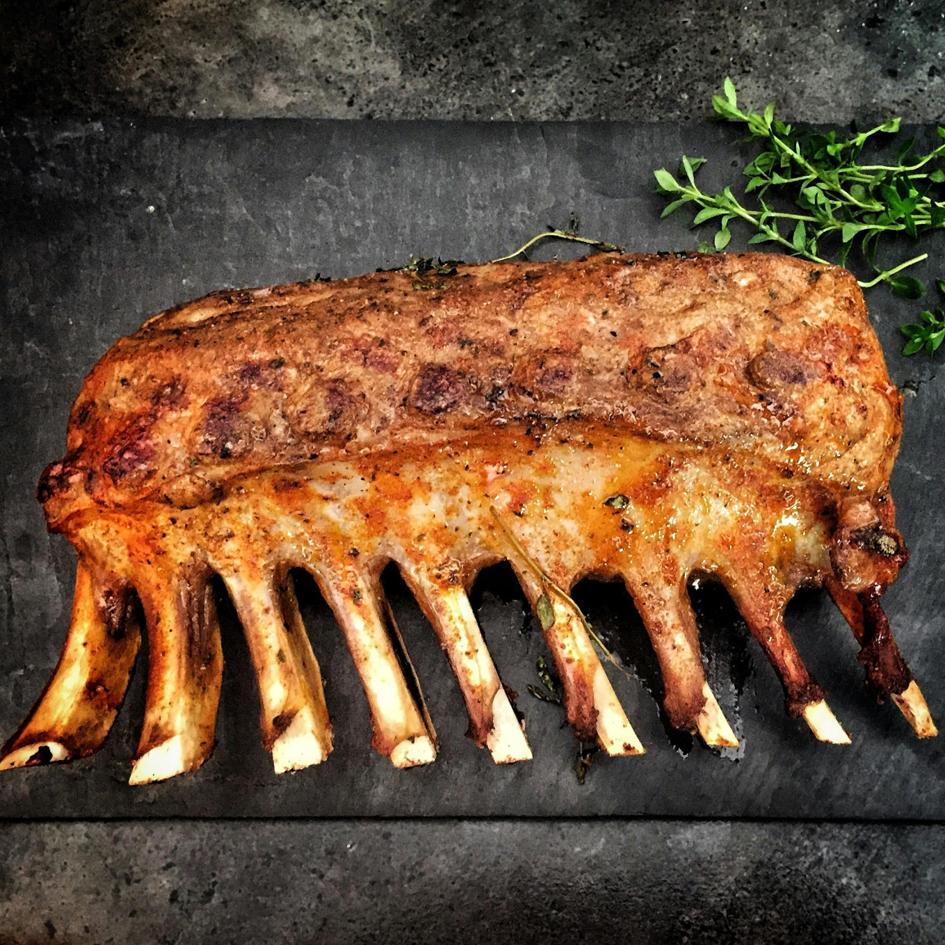 grilled rack of ribs on a dark stone surface