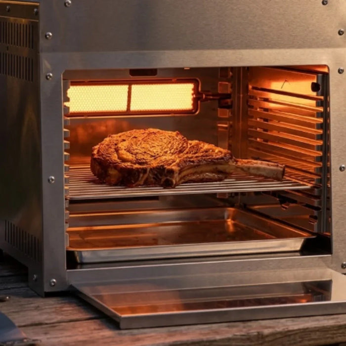 Infrared grill searing a thick steak with an even golden-brown crust at night.